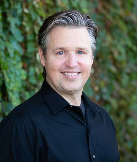 David Edwards, smiling, in front of an ivy-covered wall